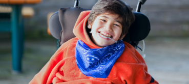 A child with cerebral palsy in a wheelchair at the dentist, smiling brightly.