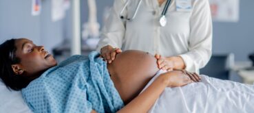 A doctor examining a pregnant woman's abdomen during a prenatal checkup.